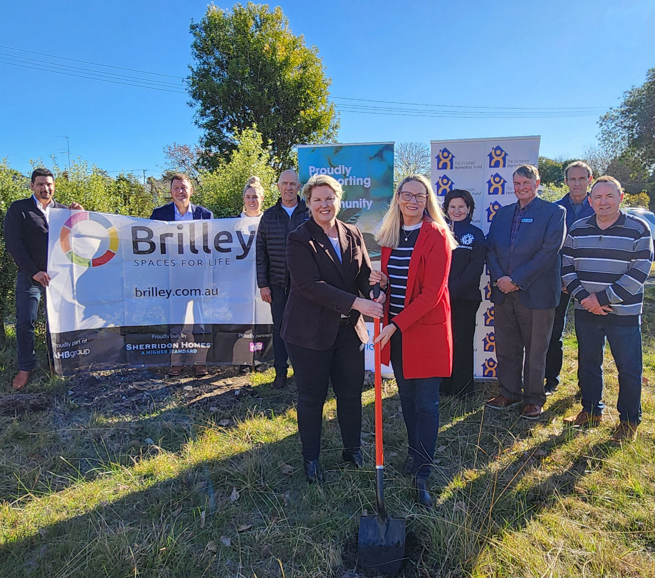 A group of smiling people turning the first sod on a new social housing project in the Latrobe Valley. Two women at the front are holding a shovel.