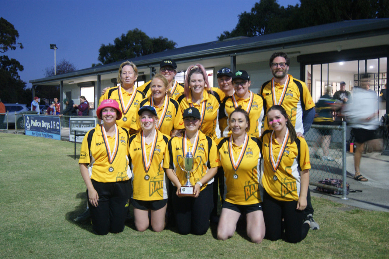 A group shot of the Raiders women's cricket team in their uniforms wearing medals,