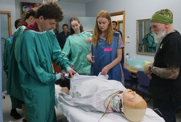 Participants in OR scrubs attend to a dummy in a practice theatre.